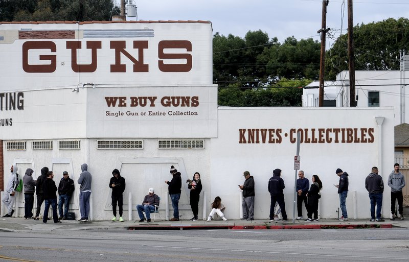 In this March 15, 2020, file photo, people wait in line to enter a gun store in Culver City, Calif. Los Angeles County Sheriff Alex Villanueva, who was sued by gun-rights groups after trying to shut down firearms dealers in the wake of coronavirus concerns, said Monday, March 30, that he is abandoning the effort. (AP Photo/Ringo H.W. Chiu, File)