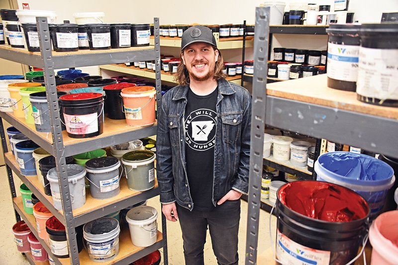 Caleb Harris, senior vice president of business development for Ink Custom Tees, stands in the ink room. Harris and the staff launched the They Will Not Go Hungry campaign and, in a little over a week, have raised more than $2,000 for food banks in Arkansas.
