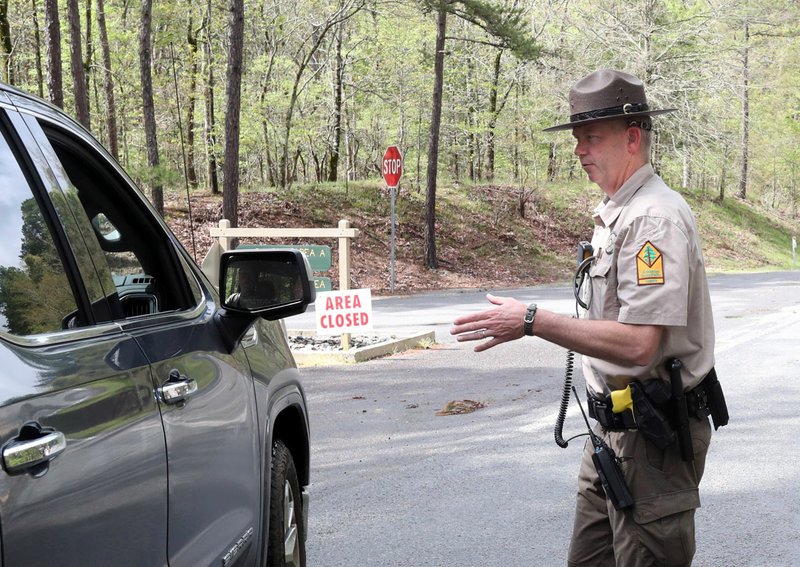 Arkansas State Park Ranger Jason Parrie talks to visitors trying to enter at a checkpoint near the entrance to Lake Ouachita State Park Friday. Parrie was turning everyone away because the park was closed Friday until further notice due to a report that three campers who had recently stayed at the park have tested positive for COVID-19. - Photo by Richard Rasmussen of The Sentinel-Record