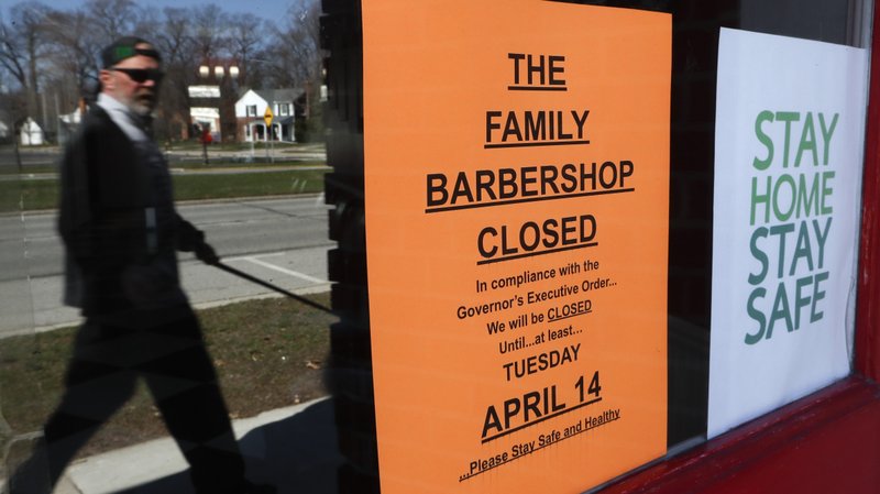 A pedestrian walks by The Family Barbershop, closed due to a Gov. Gretchen Whitmer executive order, in Grosse Pointe Woods, Mich., on Thursday. The coronavirus COVID-19 outbreak has triggered a stunning collapse in the U.S. workforce with millions of people losing their jobs in the past two weeks and economists warn unemployment could reach levels not seen since the Depression, as the economic damage from the crisis piles up around the world. - AP Photo/Paul Sancya