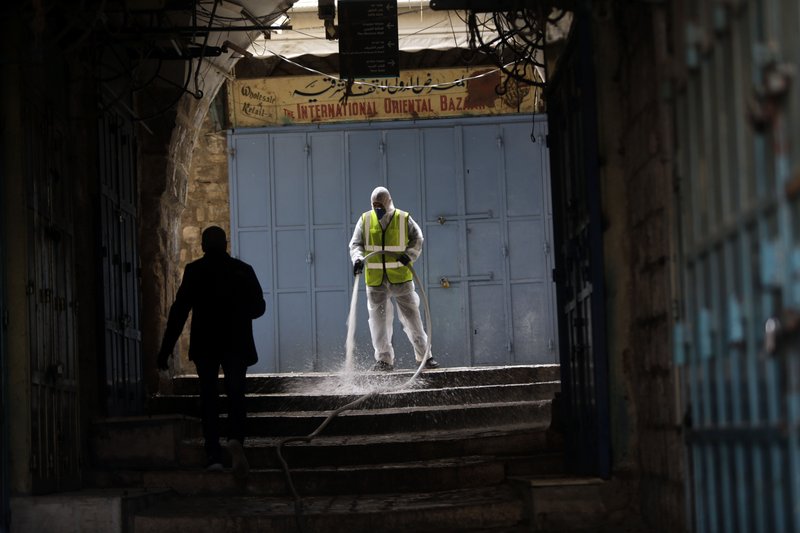 A worker disinfects an alley in Jerusalem's Old City, as general public movements are limited to prevent the spread of coronavirus, Monday, March 30, 2020. (AP Photo/Mahmoud Illean)