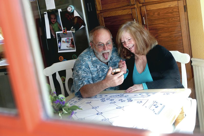 Seen through their kitchen window, Allan and Debbie Cameron contact their grandchildren via the internet March 25 in Chandler, Ariz. Debbie, 68, has asthma which makes her one of the people most at risk from the new coronavirus. The Camerons now she see their children and grandchildren from the other side of a window or a phone. (AP/Matt York)