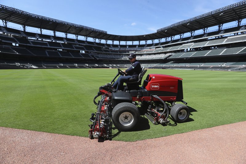 Atlanta Braves field manager Anthony DeFeo mows the grass Wednesday in the outfield in the team's newly renamed Truist Park in Atlanta. The Braves were supposed to host their home opener this Friday, but the season's start was postponed by Major League Baseball because of the coronavirus pandemic. - Photo by Curtis Compton of Atlanta Journal-Constitution via The Associated Press 