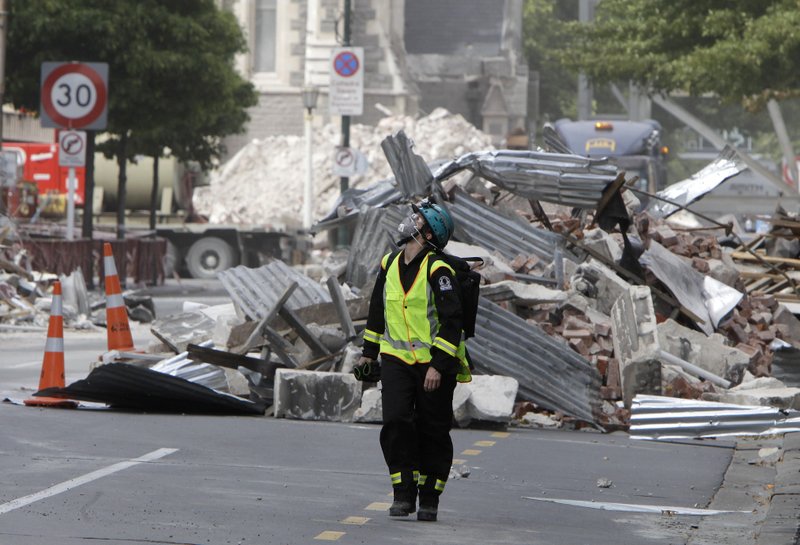 FILE- In this March 2, 2011, file photo, a New Zealand Urban Search and Rescue worker walks through the central business district during a search of earthquake damaged buildings in Christchurch, New Zealand. The virus outbreak is compromising the ability of nations to prepare for natural disasters and deal with the aftermath. Every year, the world contends with devastating typhoons, wildfires, tsunamis and earthquakes. (AP Photo/Mark Baker Pool, File)