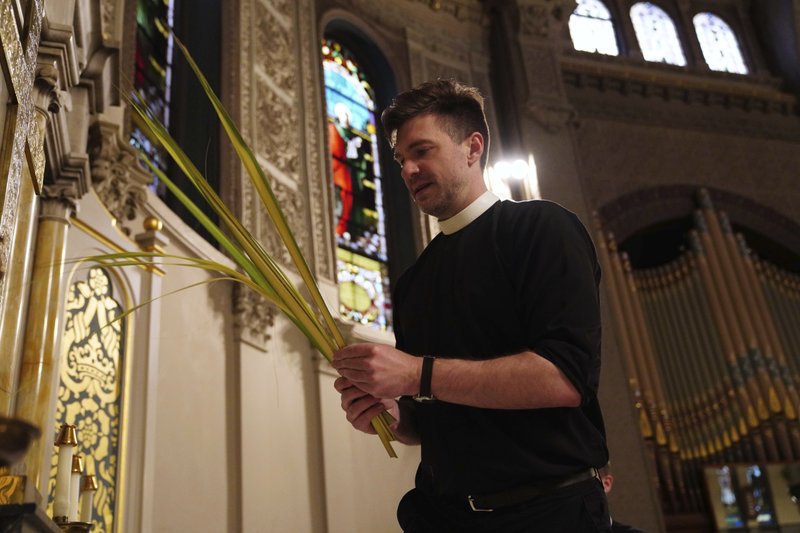 Rev. Steven Paulikas decorates an altar with palm fronds on March 29 for Palm Sunday, which will be commemorated virtually this year, at All Saints' Episcopal Church in the Brooklyn borough of New York. The global coronavirus pandemic is upending the season's major religious holidays, forcing leaders and practitioners across faiths to improvise. - AP Photo/Emily Leshner