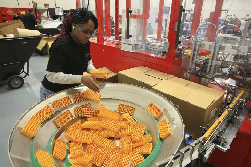 An employee adds ammunition trays to a hopper on a packaging machine at the Sig Sauer plant in Jacksonville in 2018.
(Arkansas Democrat-Gazette file photo)