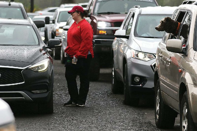 Jana Taylor takes strawberry orders from customers sitting in their vehicles Saturday at Holland Bottom Farm in Cabot. More photos at www.arkansasonline.com/45berries/. (Arkansas Democrat-Gazette/Thomas Metthe) 