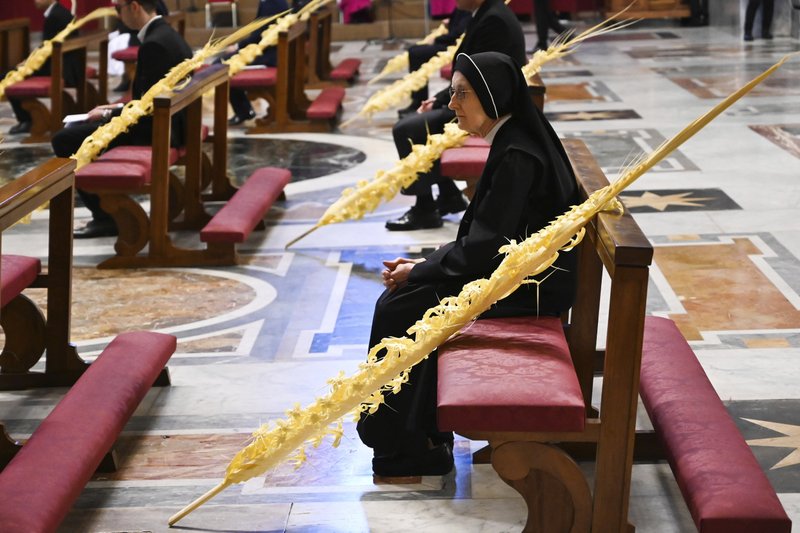 A nun sitting by a palm branch attends the Pope's Palm Sunday Mass behind closed doors in St. Peter's Basilica at the Vatican on Sunday during the lockdown aimed at curbing the spread of the COVID-19 infection, caused by the novel coronavirus. - AP Photo/pool/Alberto Pizzoli