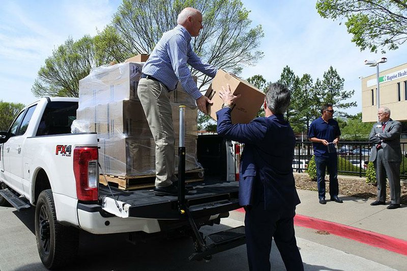 Larry Balch (in truck), former site leader with Glatfelter Advanced Materials in Fort Smith, and Tim Allen, president and chief executive officer of the Fort Smith Regional Chamber of Commerce, unload boxes of sanitary wipes from Rockline Industries at Baptist Health-Fort Smith last week. On the sidewalk, Bruce Stanton (left), fishing division vice president/general manager for Pradco Outdoor Brands, confers with Harrison Dean, Baptist Health region president for western Arkansas and eastern Oklahoma. 
(Arkansas Democrat-Gazette/Thomas Saccente) 
