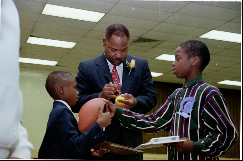 Bobby Mitchell signs memorabilia during ceremonies honoring him at Langston on Oct. 18, 1997. - File photo by Richard Rasmussen of The Sentinel-Record