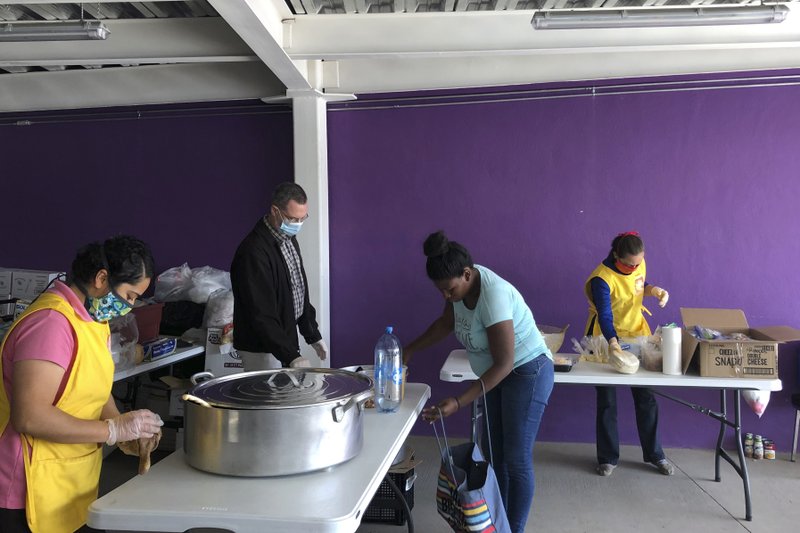 The Associated Press MASKED MEALS: In this Friday photo provided by the Kino Border Initiative, a migrant picks up a meal from masked workers at the organization's site in Nogales, Mexico near the border with the United States, amid the global COVID-19 coronavirus pandemic.