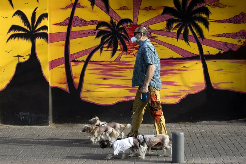 A man wears a face mask Monday as he walks several dogs in Tel Aviv, Israel. (AP/Oded Balilty) 