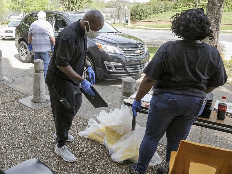 Kim Williams (left) and Cheree Buchanan hand out tablet computers Monday, April 6, 2020, at Little Rock Central High School as the Little Rock School District began distributing computers to students forced into remote learning.