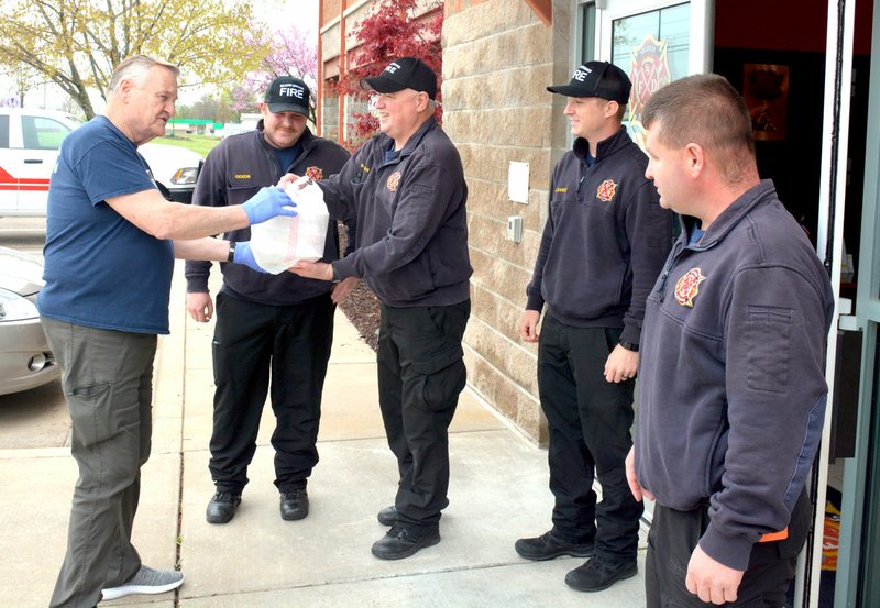 Marc Hayot/Herald Leader Larry Kenmore (left), hands a bag with meals prepared by La Hacienda to Lt. Brett Duncan as Capt. John Gideon, firefighter Blake Alexander and Battalion Chief Adam Rusk look on. Firefighters work 48-hour shifts so Kenmore and Tim Davis delivered food on Friday, Saturday and Monday to all three fire stations in order to feed all three shifts of firefighters. 