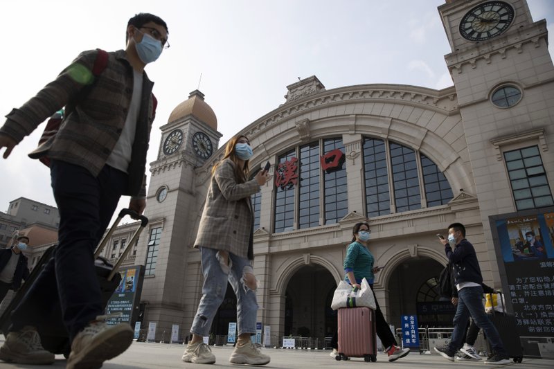 Travelers with their luggage walk past the Hankou railway station on the eve of its resuming outbound traffic in Wuhan in central China's Hubei province on Tuesday, April 7, 2020. Starting Wednesday, residents of Wuhan will be allowed to once again travel in and out of the sprawling city where the coronavirus pandemic began, ending an 11-week lockdown. (AP Photo/Ng Han Guan)