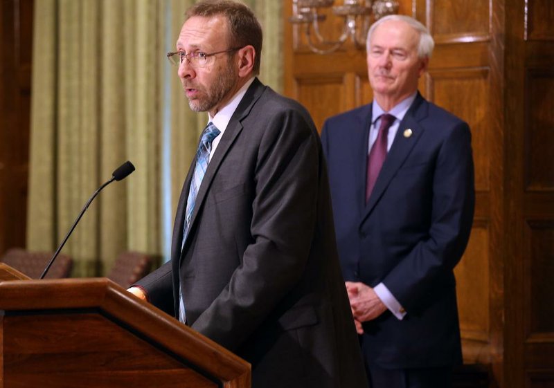FILE — Dr. Nate Smith (left), Secretary of Health, gives the new numbers of covid-19 cases as Gov. Asa Hutchinson looks on during a press briefing on Wednesday, April 8, 2020, at the state Capitol in Little Rock. 
