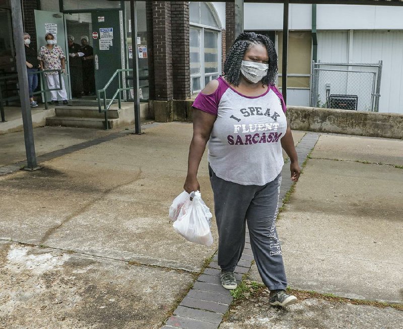 Desiree Dozier leaves Booker Arts Magnet Elementary School on Tuesday afternoon carrying two meals provided by cafeteria work- ers. The Little Rock School District is providing food for students. (Arkansas Democrat-Gazette/John Sykes Jr.) 
