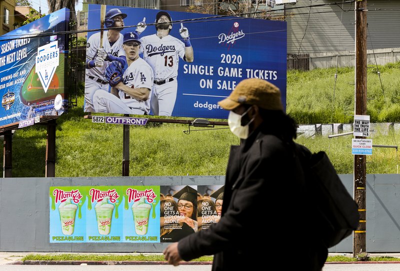 A pedestrian wears a hat and a face mask April 2 on Sunset Blvd., in the Echo Park neighborhood of Los Angeles. Major League Baseball opening day was to have been March 26, but was pushed back to mid-May at the earliest because of the coronavirus outbreak. The spring training schedule was cut short on March 12 because on the pandemic, and it remains unclear when and if baseball can resume. - Photo by Damian Dovarganes of The Associated Press 