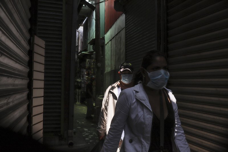 People, wearing protective face masks, make their way through a popular market in Managua, Nicaragua, Tuesday, April 7, 2020. Restaurants are empty, there's little traffic in the streets and beach tourists are sparse headed into Holy Week despite the government's encouragement for Nicaraguans to go about their normal lives. (AP Photo/Alfredo Zuniga)