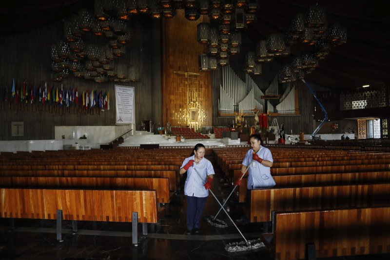 Cleaning staff mop the floor of the Basilica of Our Lady of Guadalupe, which was closed to the public to prevent the spread of coronavirus, in Mexico City, on Good Friday, April 10, 2020. Instead of celebrating with the usual packed churches and elaborate processions attended by thousands, this year Mexico's Catholic faithful were told to stay home, with closed-door Masses and a private performance of the Stations of the Cross broadcast on television. (AP Photo/Rebecca Blackwell)