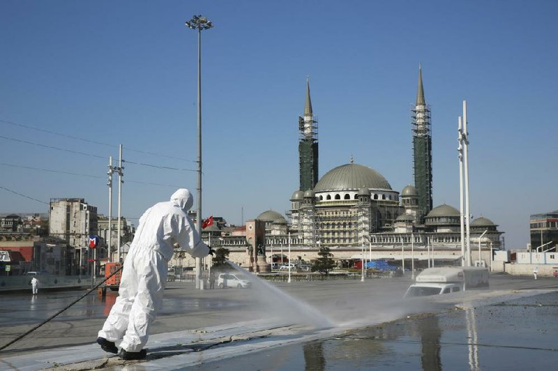 Workers disinfect surfaces in Istanbul’s Taksim Square on Sunday in this photo provided by the city mayor’s office. More photos at arkansasonline.com/413turkey/. (AP) 
