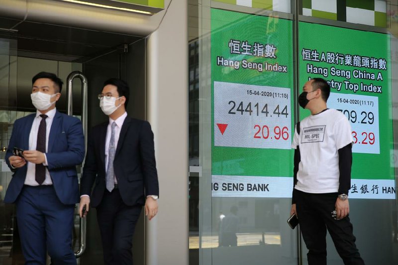 People in Hong Kong pass an electronic board showing the Hong Kong share index outside a bank Wednesday. Stocks edged lower after more evidence of economic damage being caused by the coronavirus outbreak was reported.
(AP/Kin Cheung)