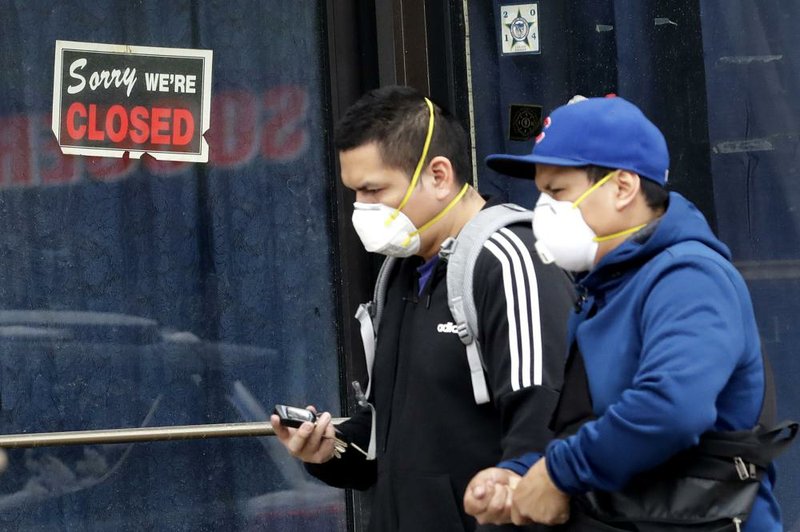 Men pass a closed retail store in Chicago on Wednesday. With businesses across America shut down, economists are projecting a record-breaking 40% annualized drop in U.S. economic output for the April-June quarter.
(AP/Nam Y. Huh)