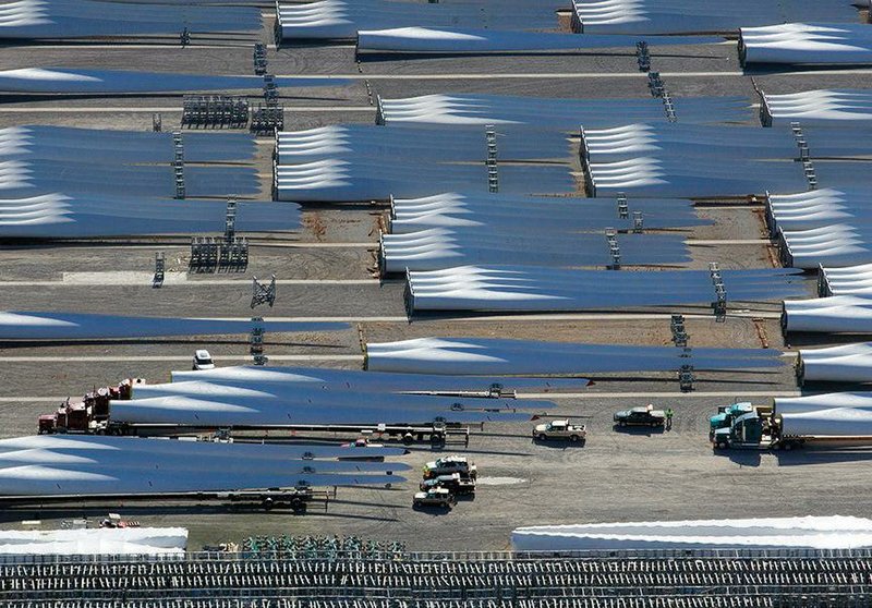 Trucks (bottom) prepare to haul some of the thousands of wind turbine blades sitting on the lot at the LM Wind Power manufacturing plant in November 2014 at the Port of Little Rock. The plant, which opened in 2008, will cease manufacturing at the end of the month, officials said Tuesday. (Democrat-Gazette file photo) 