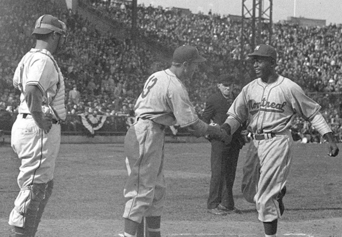 In this April 18, 1946, file photo, Montreal Royals’ Jackie Robinson (right) is congratulated by teammate George Shuba as he crosses home to score against the Jersey City Giants at Roosevelt Stadium.