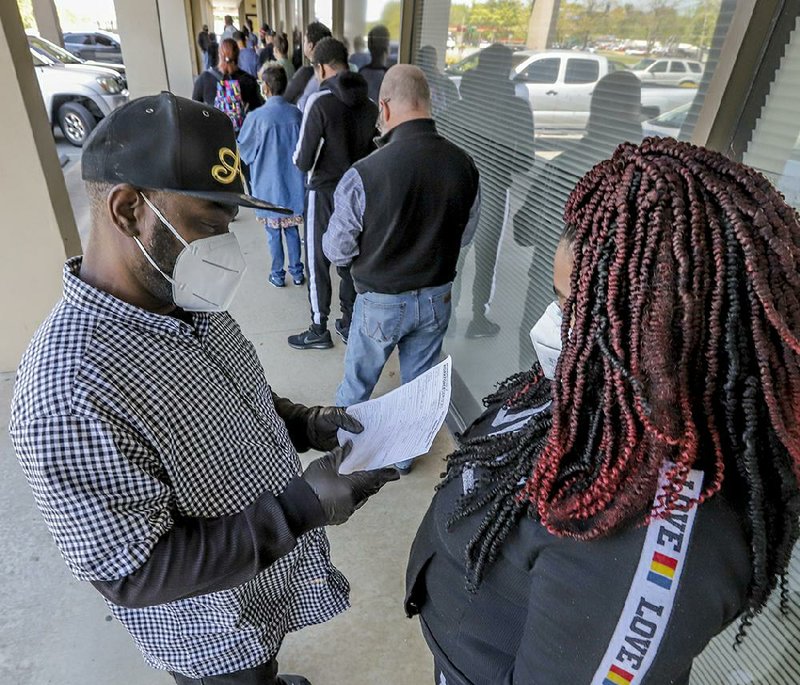 Keith Davis and his friend Jaki Hart wait in line Thursday outside the Arkansas Workforce Center at 5401 S. University Ave., in Little Rock. They said they were filing for unemployment because of coronavirus-related layoffs. About 150,000 unemployment benefit claims have been processed in Arkansas since the first week of March, Gov. Asa Hutchinson said Thursday. More photos at arkansasonline.com/417job/.
(Arkansas Democrat-Gazette/John Sykes Jr.)