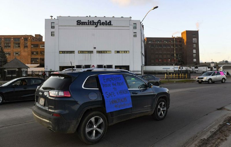 A vehicle bearing a sign calling for a safe and healthy workplace drives past a Smithfield Foods plant in Sioux Falls, S.D., during a protest last week. A surge of coronavirus cases at Smithfield Foods has highlighted the vulnerability of meat processing workers.
(The Argus Leader/Erin Bormett)