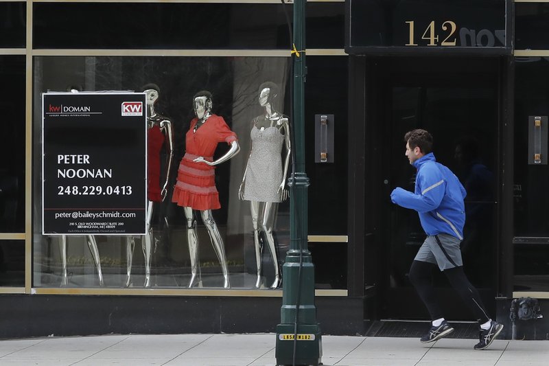A jogger runs past Rococo, a clothing store, Thursday, April 16, 2020, in Birmingham, Mich. The government's lending program for small businesses is on hold. The Small Business Administration said Thursday that it reached the $349 billion lending limit for the program, after approving nearly 1.7 million loans. (AP Photo/Carlos Osorio)