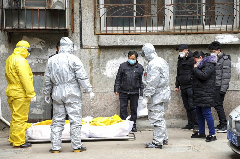 In this Feb. 1, 2020, file photo, funeral home workers remove the body of a person suspected to have died from the coronavirus outbreak from a residential building in Wuhan in central China's Hubei Province. (Chinatopix via AP, File)