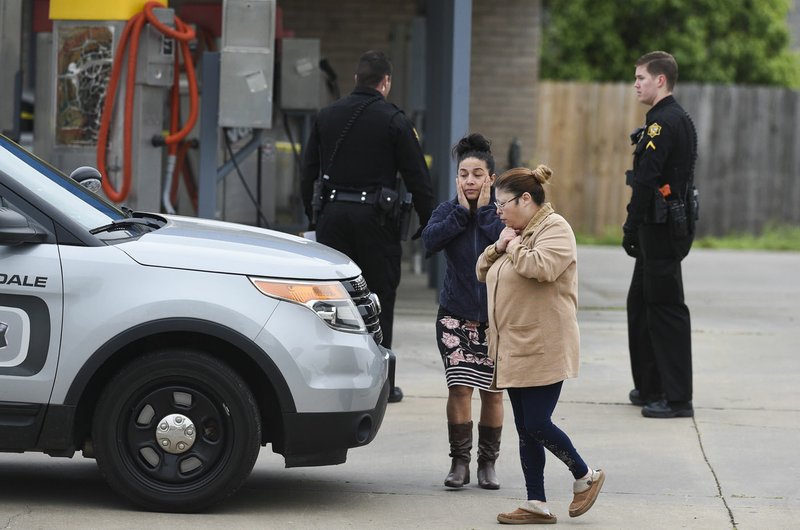 Yesnia Santos (from center left) and Yvonne Martinez react at the scene of a fatal shooting Friday at a car wash behind the Valero gas station at 3818 Elm Springs Road in Springdale. Go to nwaonline.com/200418Daily/ for today's photo gallery. (NWA Democrat-Gazette/Charlie Kaijo)