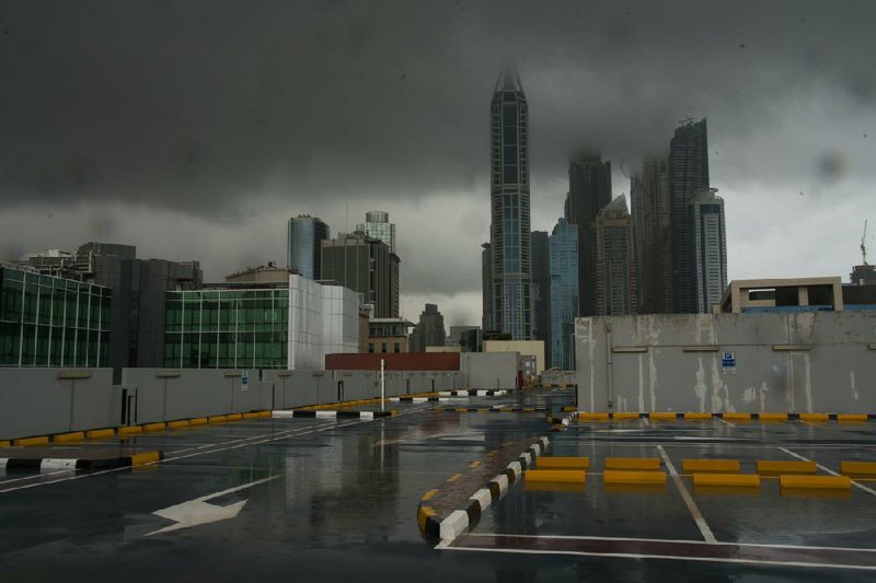 Storm clouds cover up the tops of buildings in the Dubai Marina as rain falls on a parking lot that stands empty over the coronavirus pandemic in Dubai, United Arab Emirates, on Wednesday. Middle East economies, already wracked by high numbers of unemployed youth, unrest, conflict and large numbers of refugees, will sink into a recession this year sparked by the double shock of the coronavirus outbreak and low oil prices, the International Monetary Fund said Wednesday.
(AP/Jon Gambrell)