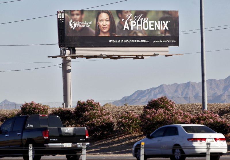 FILE - In this Nov 24, 2009 file photo, a University of Phoenix billboard is shown in Chandler, Ariz. Some of the nation&#x2019;s largest for-profit colleges are ramping up advertising, hiring recruiters and offering discounts for online classes as they predict that the coronavirus will steer more Americans back to school, helping revive the industry. (AP Photo/Matt York, File)