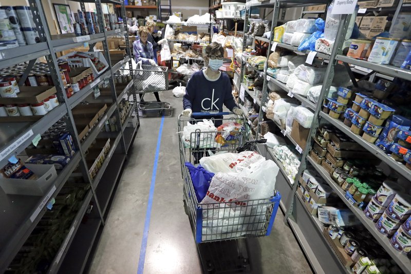 Laura Burbank, a worker at GraceWorks Ministries food pantry in Franklin, Tenn., pushes a cart for a family earlier this month. More photos at arkansasonline.com/420pantries/. (AP/Mark Humphrey) 
