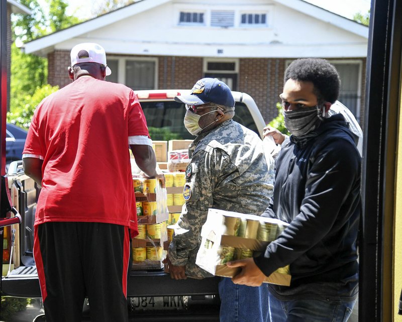 Gregg Andrews, center, and Bryce Burris, right, help unload a shipment of food at the Webb Community Center on Monday. The food will be distributed to the community, free of charge. - Photo by Grace Brown of The Sentinel-Record