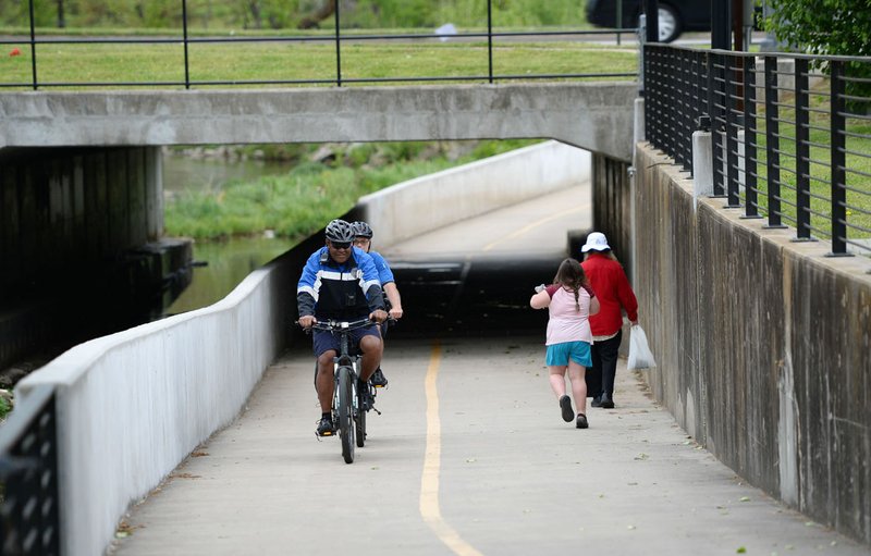 Robert Aini (from left) and Mike Hignite, both with Springdale;s Police Department, ride Wednesday past pedestrians while patrolling along the Razorback Greenway in Springdale. The city's Trails Committee will hear an update on BikeNWA protected bike lanes. Go to nwaonline.com/2004223Daily/ for today's photo gallery. (NWA Democrat-Gazette/Andy Shupe)