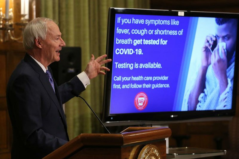 Gov. Asa Hutchinson, during his daily briefing Thursday at the state Capitol, shows an ad for a new campaign aimed at getting more people tested for the coronavirus.
(Arkansas Democrat-Gazette/Thomas Metthe)