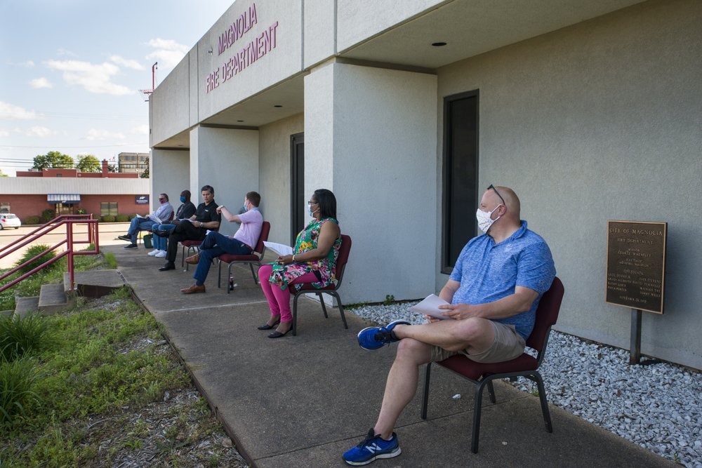 Magnolia City Council members, most of whom were masked, sit outside of their normal meeting chambers on Thursday, April 23, during a specially-called meeting.