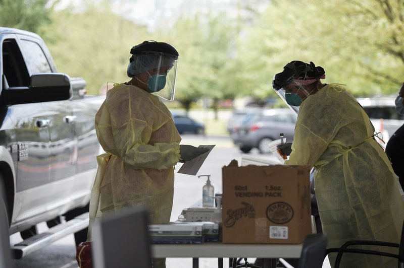 Nurses Julie Palmer (left) and Caitlin Percival prepare covid-19 test kits Friday at a drive-through testing site at the Mercy Convenient Care in Bentonville. Go to nwaonline.com/200425Daily/ for today's photo gallery. (NWA Democrat-Gazette/Charlie Kaijo)