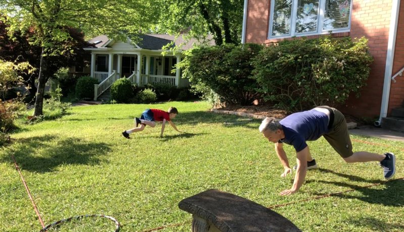 Daniel Carnahan and his 8 1/2-year-old son, Owen, do the final leg of the Box Hop Race -- the bear crawl -- for Matt Parrott's Master Class on their lawn in Little Rock. (Arkansas Democrat-Gazette/Celia Storey) 