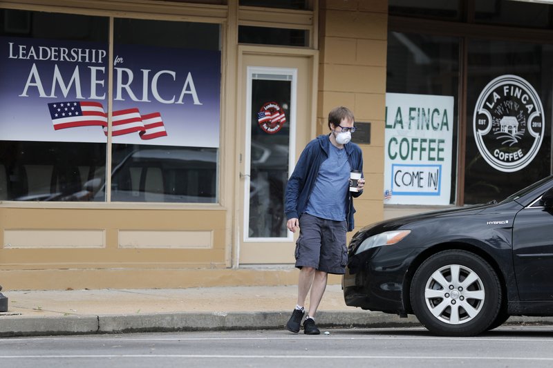 A man wearing a protective face mask leaves a coffee shop Wednesday, April 29, 2020, in Eureka, Mo. Eureka Mayor Sean Flower is encouraging business in the town of roughly 10,000 to reopen when the state of Missouri eases restrictions put in place to control the spread of the coronavirus next week despite the fact that St. Louis County, where Eureka is located, has extended its stay-at-home order until at least mid-May. (AP Photo/Jeff Roberson)