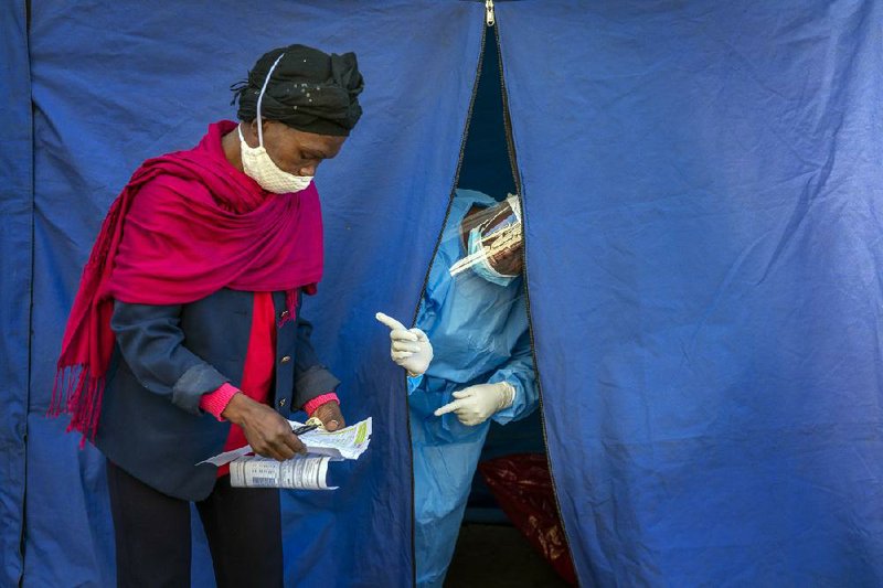 Health officials in downtown Johannesburg check the listings Thursday of people who are to be tested for covid-19, as well as HIV and tuberculosis.
(AP/Jerome Delay)