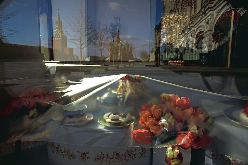 In this photo taken on Wednesday, April 22, 2020, Mock-ups of desserts and flowers are covered by polyethylene as Bosco Cafe is closed in Red square, with the reflections of St. Basil's Cathedral (center) and Spasskaya Tower, in Moscow. The Kremlin's anti-crisis measures reflect both its long-held emphasis on state-controlled companies and a fear of opening state coffers at a time when government revenue is drying up due to a plunge in oil prices and economic slump. (AP/Pavel Golovkin)