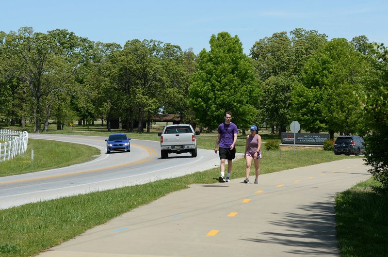 Traffic and pedestrians travel Friday along Garland Avenue past the University of Arkansas farm in Fayetteville. City officials are making a final push to finish widening Garland Avenue along the University of Arkansas Agri Farm and complete a project that began decades ago. Plans call for a four-lane divided road with a raised medium, sidewalk and bike trail, and a roundabout to access university Division of Agriculture facilities. Visit nwaonline.com/200503Daily/ for today's photo gallery. (NWA Democrat-Gazette/Andy Shupe)