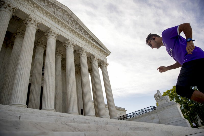 A man exercises on the steps of the Supreme Court where the justices will hold arguments by telephone for the first time ever, Monday, May 4, 2020, in Washington. (AP Photo/Andrew Harnik)