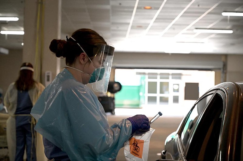 National Guard Senior Airman Marie Dahlke, a registered nurse, finishes packaging a covid test at the drive-thru screening center at UAMS in Little Rock in this Monday, May 4, 2020, file photo. (Arkansas Democrat-Gazette/Stephen Swofford)