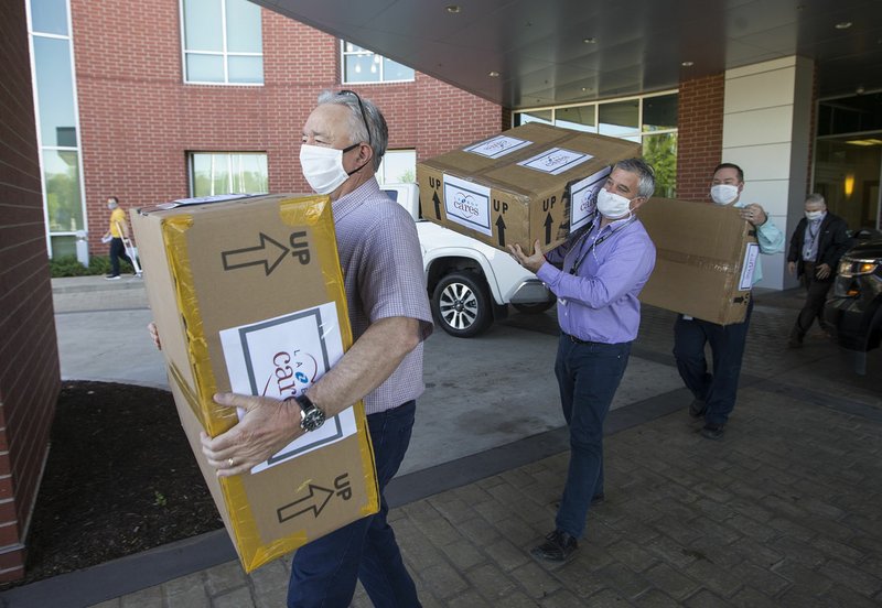 Mike Wilmon (from left), Paul Dilbeck and Neil Erter with La-Z-Boy unload boxes of masks at Siloam Springs Regional Hospital in this Wednesday, April 29, 2020, file photo. La-Z-Boy, who operates a plant in Siloam Springs, donated 10,000 masks to Northwest Health to be used at all five of the system's hospitals in Northwest Arkansas as well as their covid-19 testing centers. (Ben Goff/NWA Democrat-Gazette)